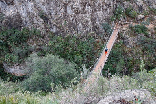 A woman wearing a pack hikes across the hanging bridges in the beautfiul limestone canyons near Chulilla, Spain.