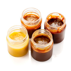Set of homemade caramel sauces in jars isolated on white background