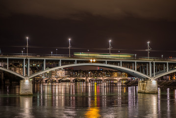 Tram running over Wettsteinbrucke bridge on long exposure with reflection in the Rhein river and night city lights