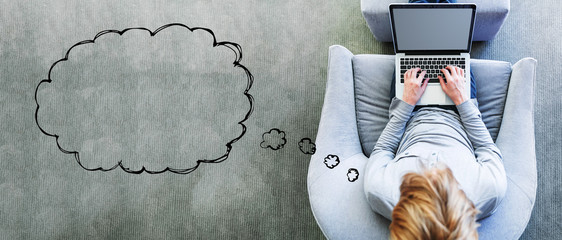 Blank speech bubble with man using a laptop in a modern gray chair