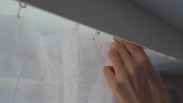 women's hands take the curtain off the hooks, the tulle is removed from the cornice for washing. The process of cleaning the apartment.