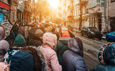 Many unidentified people are waiting for city transport at the bus stop