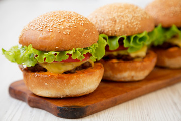 Homemade cheeseburgers on rustic wooden board, side view. Close-up. Selective focus.