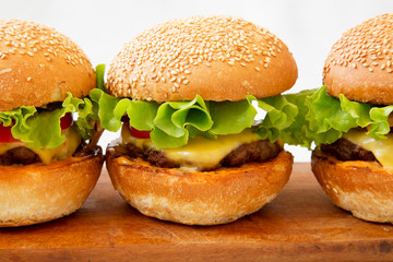Homemade cheeseburgers on rustic wooden board, side view. Close up.
