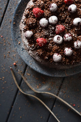 Tasty chocolate cake with chocolate icing and raw berries with vintage forks on dark background