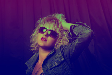 Portrait of a young elegant girl with glasses in neon light. Beautiful blond woman with red lips. Photo stylized toning.