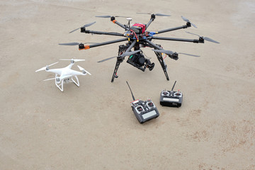 Octocopter and quadcopter with two control panels on a beige background before take-off. Unmanned aerial vehicles on the ground. Aerial drone.