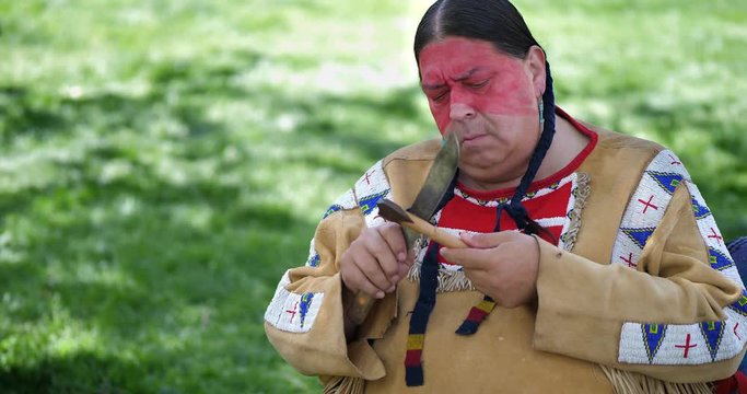 Native American Indigenous Indian tribe chief sharpens the knife at the willage, 4K