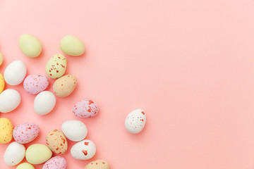 Obraz na płótnie Canvas Happy Easter concept. Preparation for holiday. Easter candy chocolate eggs and jellybean sweets isolated on trendy pastel pink background. Simple minimalism flat lay top view copy space