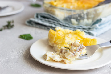 Potato casserole with fish and cheese on a light grey background.