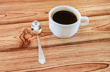 a cup of coffee and a spoon on a wooden background. Close-up