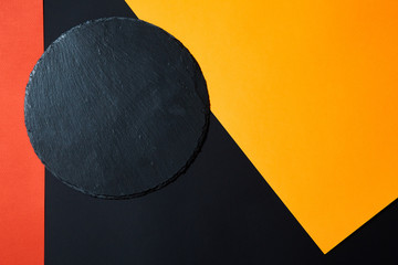 From above of empty black slate serving board on multicolored background with geometric composition