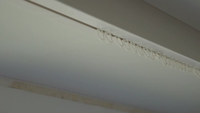 women's hands take the curtain off the hooks, the tulle is removed from the cornice for washing. The process of cleaning the apartment.