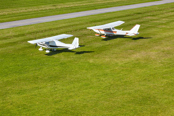two white pleasure planes on a bright sunny day on the runway of the airfield against the background of the field - 262095595