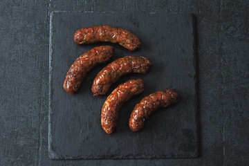 Grilled Bavarian sausages with spices on a stone board. Copy space.