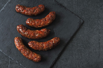 Grilled Bavarian sausages with spices on a stone board. Copy space.