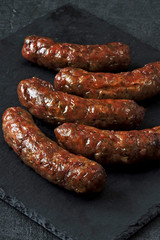 Grilled Bavarian sausages with spices on a stone board. Copy space.
