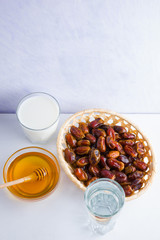 Dried dates, milk and honey on white background. Holy month of Ramadan, concept. Righteous Muslim lifestyle. Starvation. Dates in wooden basket and honey. Vegetarian food. Copy space