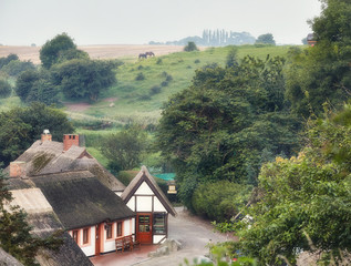 Cape Arkona, Germany. European Village Vitt. View of the houses from above. Misty summer morning. Hills and fields with grazing horses in the background. - 262096761