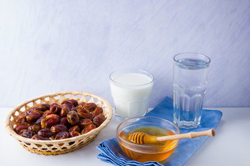 Dried dates, milk and honey on white background. Holy month of Ramadan, concept. Righteous Muslim lifestyle. Starvation. Dates in wooden basket and honey. Vegetarian food. Copy space