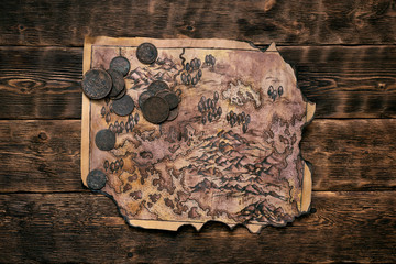 Old map and coins on a adventurer table background. Treasure hunt concept.
