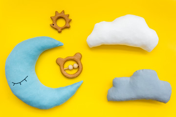Baby care concept with moon pillow, clouds and toy for sleep of newborn on yellow background top view