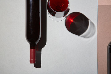Layout of bottles and glass of red wine on colorful paper background