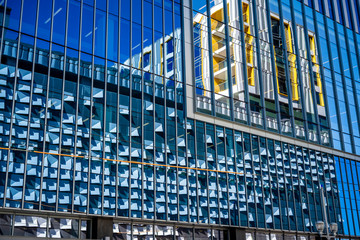 Fototapeta premium High-rise modern building with glass exterior reflects the opposite building