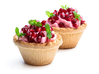 Mini tarts with pink cream and pomegranate seeds isolated on white
