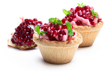 Mini tarts with pink cream and pomegranate seeds isolated on white