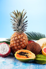 Fresh tropical Fruits on the beach with a palm leave. Assorted tropical fruits, orange,Ananas or pineapple and mango