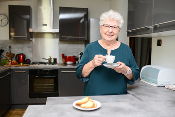 happy senior active woman drinking coffee in a modern kitchen at home