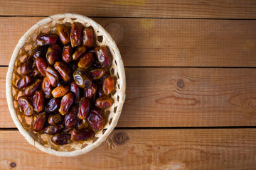 Dried dates on wooden background. Holy month of Ramadan, concept. Righteous Muslim lifestyle. Starvation. Dates in a wooden basket in the style of minimalism. Copy space
