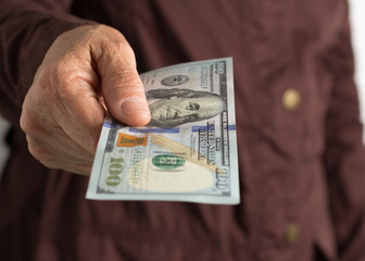 Cash bills from USA currency. Dollars. Front view of old woman's hand handling bills.