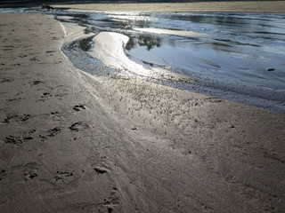 Reflections of the sun on the wet sand as the tide streams out. 