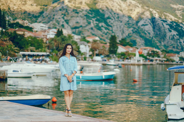 A beautiful young girl in a blue dress standing near water