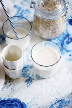 Glass of homemade vegan oat milk and jar of oats