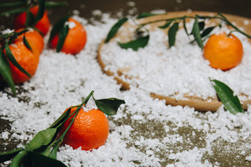 Mandarin citrus fruit with leaves on a wooden kitchen table on a blurred background. healthy food. raw food Artificial white snow. New Year. Christmas