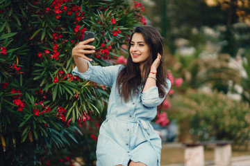 A beautiful young girl in a blue dress sitting near the flower tree