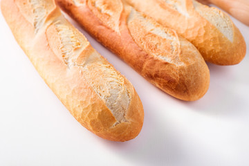 Freshly baked French baguettes on white wooden table.