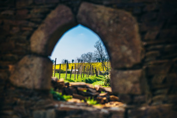 Colorful country landscape through an old stone church window