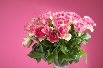 Big bouquet from red roses on a pink background