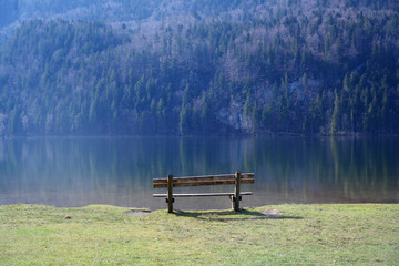 wooden bench at a mountain lake in the morning light, copy space