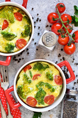Casserole with broccoli and tomatoes on a concrete background. View from above.