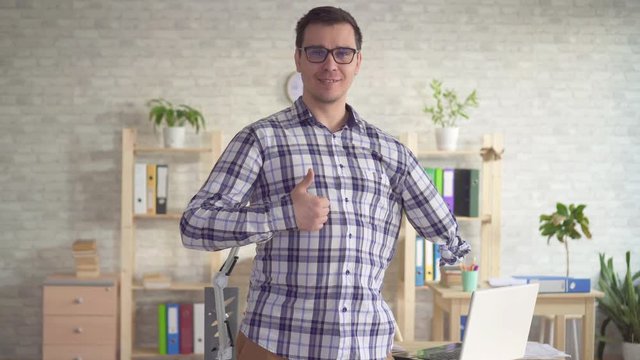 positive male disabled with an amputated hand looking in camera and smiling showing thumb up