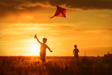 Fototapeta na wymiar Children with a kite at sunset