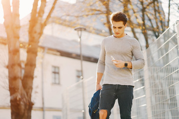 stylish man walking through the city smoking an e-cigarette