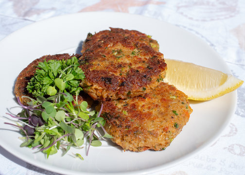 Fresh Crab Cakes Served On A White Plate With Lemon And Salad.