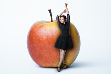 small female staying near giant apple; woman on diet,