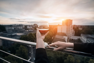 female's hand keep glass with wine in rays of sunset;